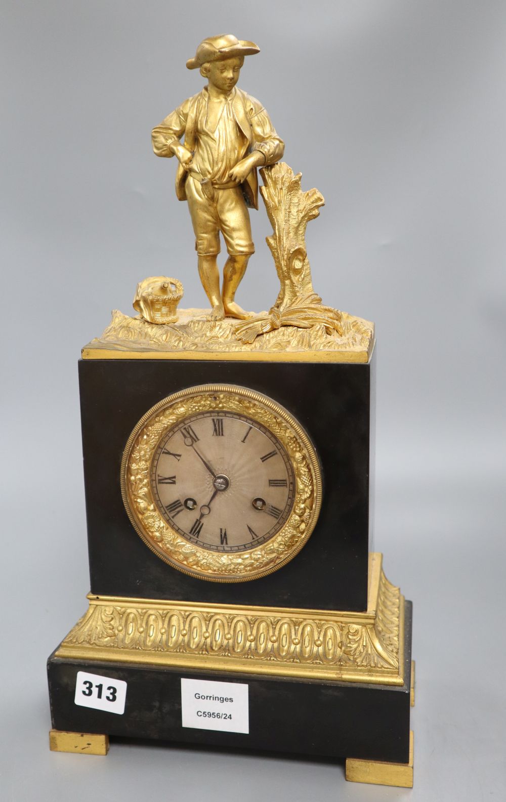 A 19th century French ormolu mounted black marble eight day mantel clock, surmounted by a figure of a youth